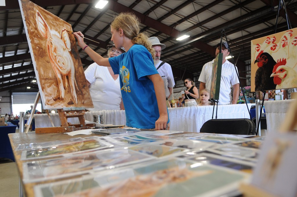 Blythe Godfrey, 11, adds her mark to an oil painting by Iwona Barlyska during the 153rd annual Chilliwack Fair at Chilliwack Heritage Park on Saturday, Aug. 9, 2025.