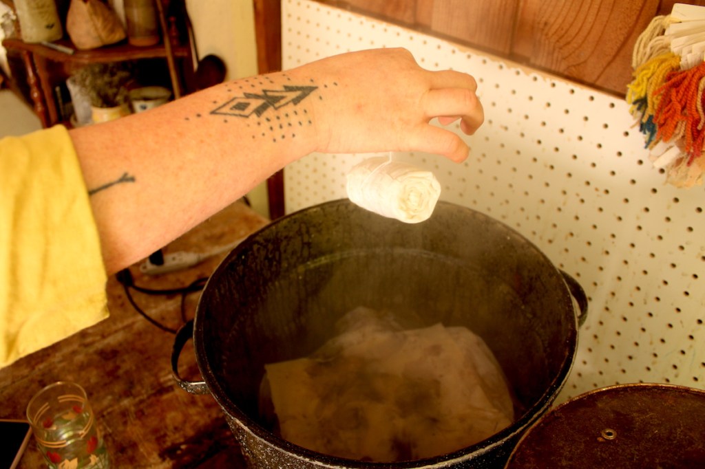 Carly Stefanowich lowers a flower-filled linen garment into a steam pot to be eco-printed.