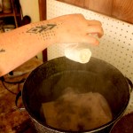 Carly Stefanowich lowers a flower-filled linen garment into a steam pot to be eco-printed.