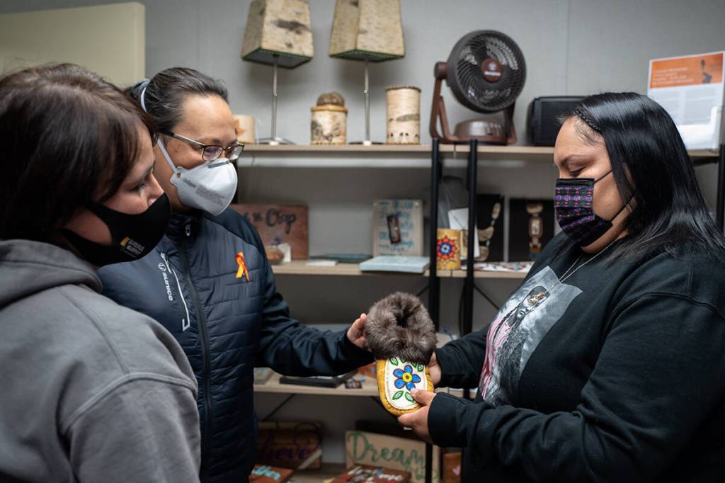 Tammy Brown (left), Lorisha Desjarlais (centre left) and Teneshia Yahey (right) admire one of the moccasins available at the CWAA Market.