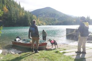 From left, Tyler McKendry, Valhalla Wilderness Society biologist Amber Peters, her dog Akash and Václav Kuželka prepare a boat at Carnes Creek to access the Rainbow-Jordan Wilderness via Lake Revelstoke, pictured Oct. 9, 2025. (Evert Lindquist/Revelstoke Review)