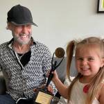 Paul Rodgers&rsquo; great niece Charlotte, three years old, presents him with the Hall of Fame statue. Rodgers, 75, was the only Canadian inducted into the Rock and Roll Hall of Fame in 2025. (Photo by Cynthia Rodgers)