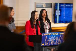 Jessie Sunner, B.C.&rsquo;s minister of post-secondary education and future skills, speaks at a news conference at the legislature on Monday, Oct. 6. Niki Sharma, the attorney general, is standing to the right in the rear. (Photo courtesy B.C. government)