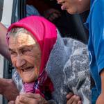 An elderly woman is helped off a bus after being relocated from the front in eastern Ukraine. (Photo by Darrell McKay)