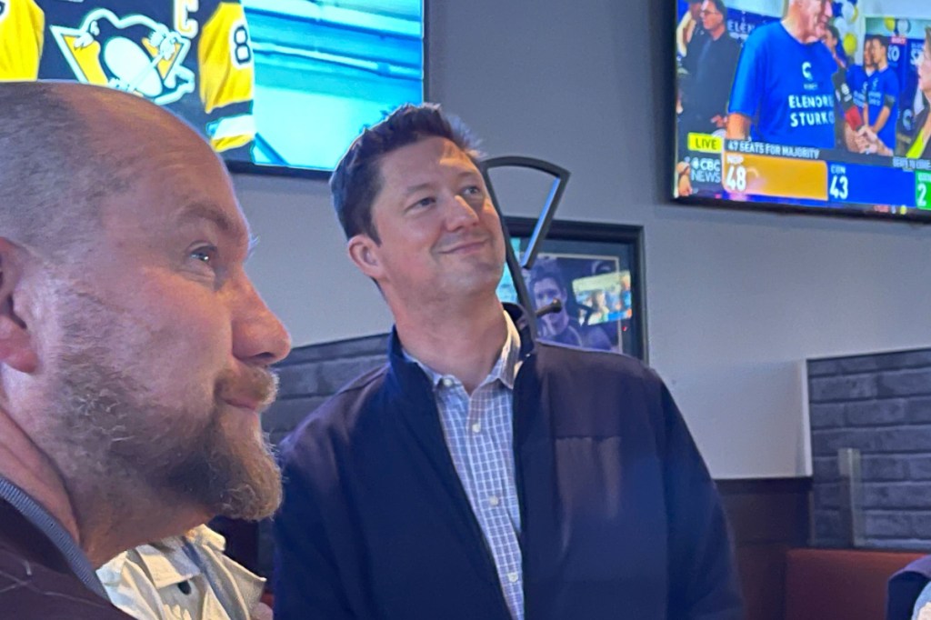 Conservative candidate Adam Hayduk, right, watches the 2024 election results at Boston Pizza in Port Alberni with his campaign manager Mike Butler.