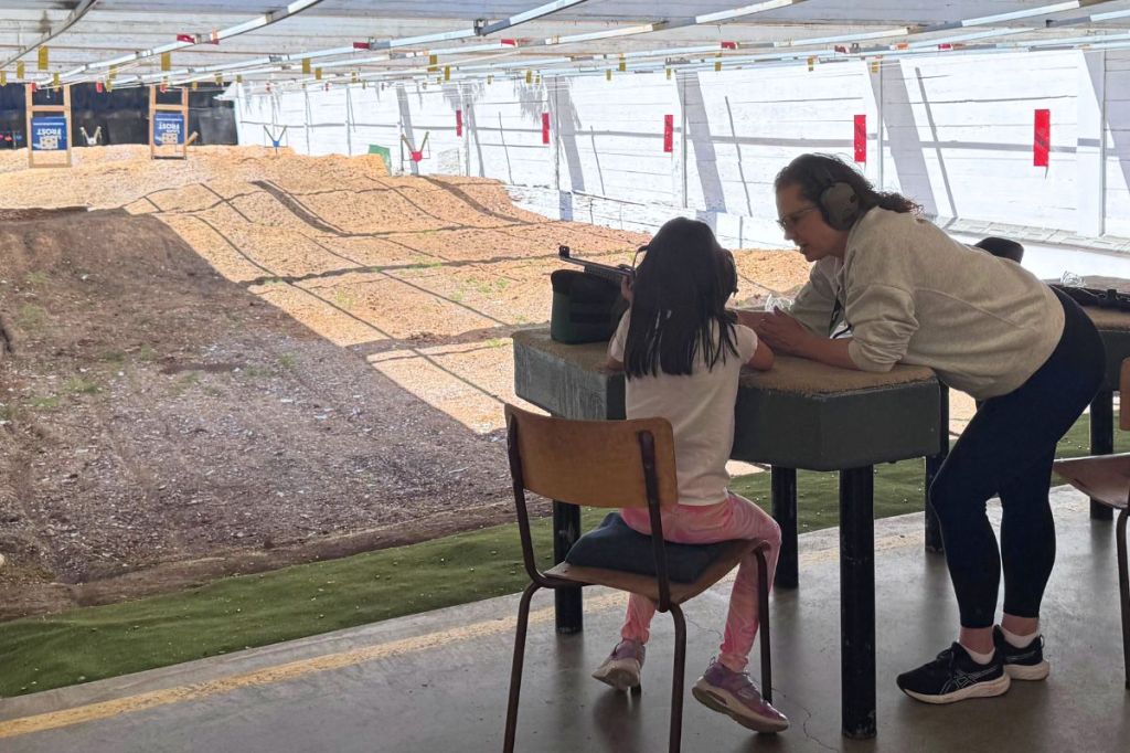A girl is getting ready to shoot her rifle downrange with one of the NSRG coaches.