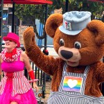 PNE mascot KC Bear dances with a fellow performer at the fair site in Vancouver on Aug. 14, 2025, during a media event. An "All Canadian Street Party" happens twice daily on Miller Drive this year, near the Sands of Wonder sand sculptures.