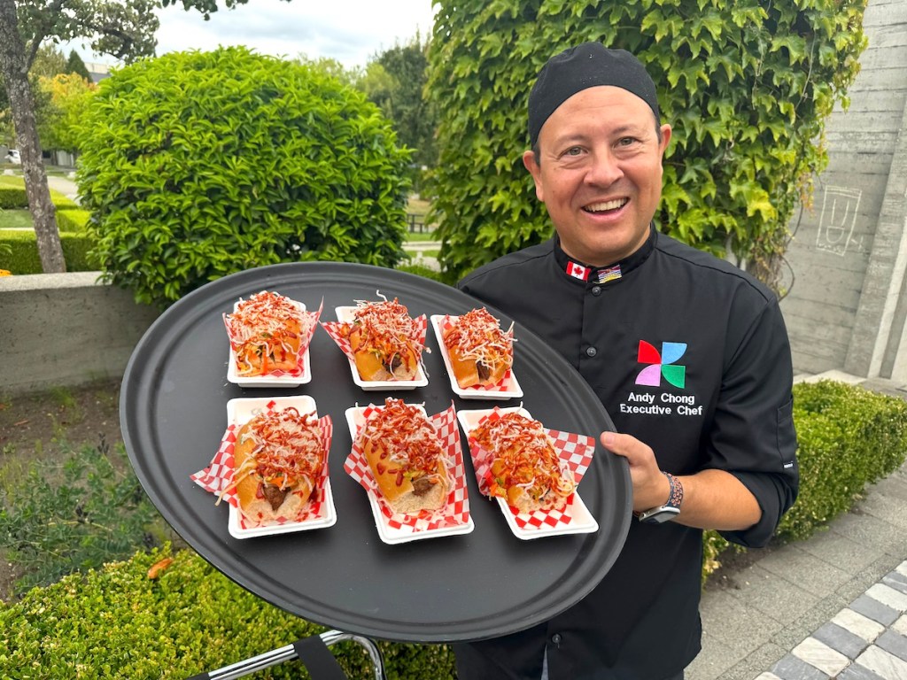 PNE executive chef Andy Chong with a plate of Diggity Dogs' Bulgogi Chicken Dogs, topped with crispy rice noodles, at the PNE fair site in Vancouver on Aug. 14, 2025.