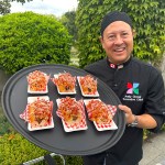 PNE executive chef Andy Chong with a plate of Diggity Dogs' Bulgogi Chicken Dogs, topped with crispy rice noodles, at the PNE fair site in Vancouver on Aug. 14, 2025.