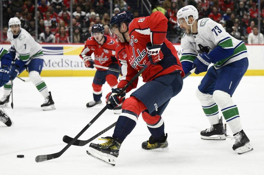Washington Capitals left wing Alex Ovechkin skates with the puck past Vancouver Canucks defenceman Vincent Desharnais (73) during the first period of an NHL hockey game, Wednesday, Jan. 8, 2025, in Washington. (AP Photo/Nick Wass)