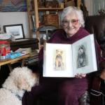 For Elain Genser, canine companionship is an important part of her life. Genser holds up paintings she has done of her past pets. (Samantha Duerksen/Black Press Media)