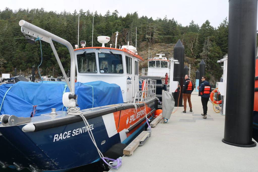 Senior manager of communications Michael Lowry and operations base manager Kyle Hujdic walk between spill response vessels docked at Beecher Bay. (Ben Fenlon/Sooke News Mirror)