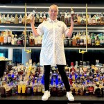 Whisky curator Stacy Kyle with bottles on the lounge shelves at Skye Avenue Kitchen & Lounge in Surrey, at the Central City tower.